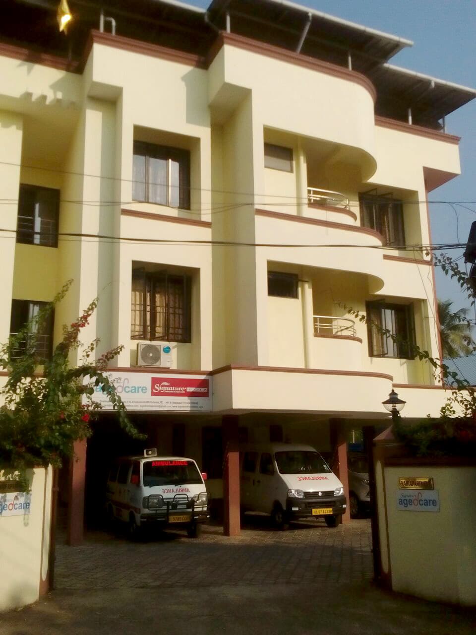 Signature AgedCare building entrance with signage and ambulances parked underneath, Kakkanad, Kerala